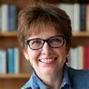 Portrait of Emily Hawthorne, a thoughtful woman with glasses and a warm smile, perhaps in a library setting.